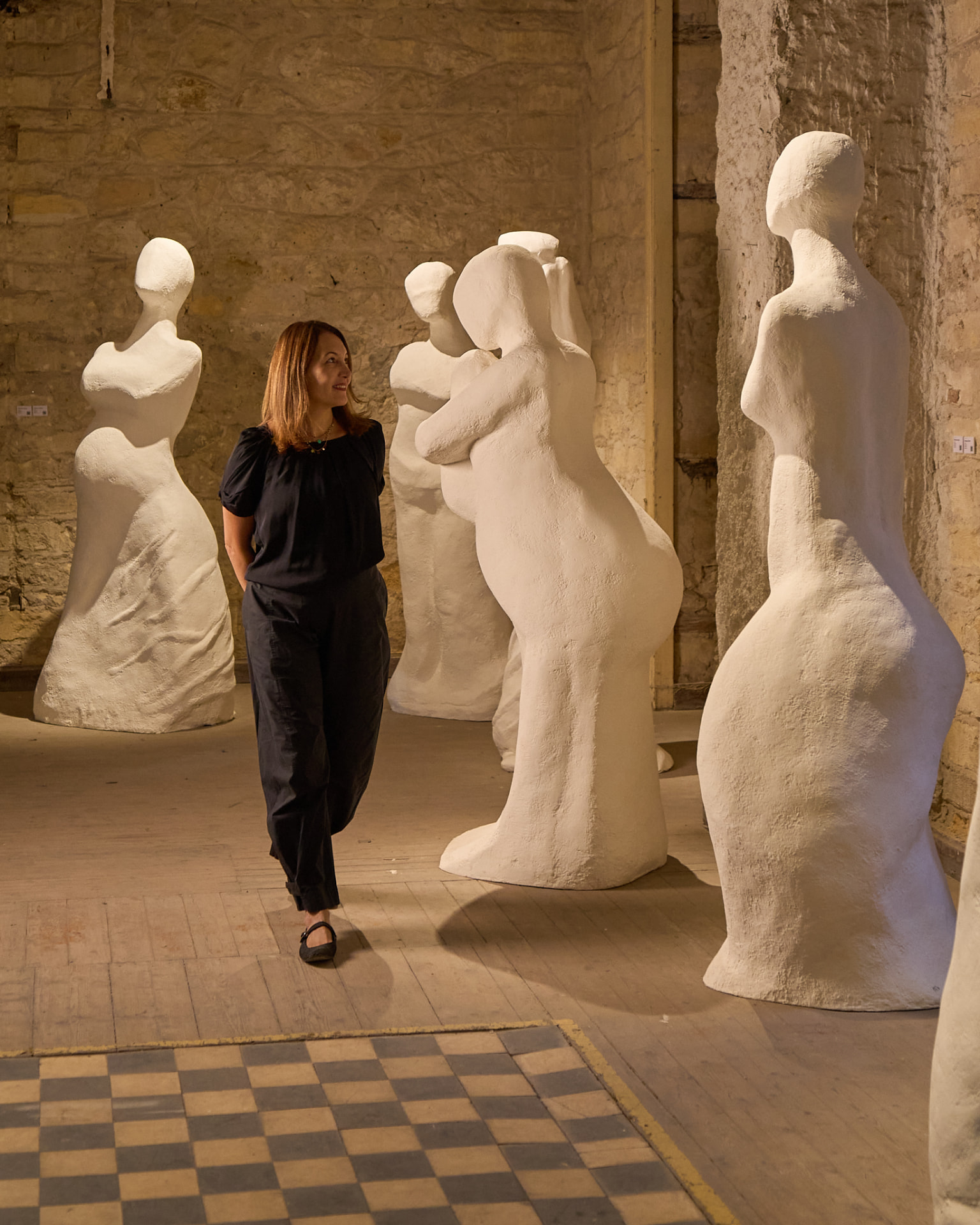 Hedayat walking among her large white plaster figure sculptures in the studio