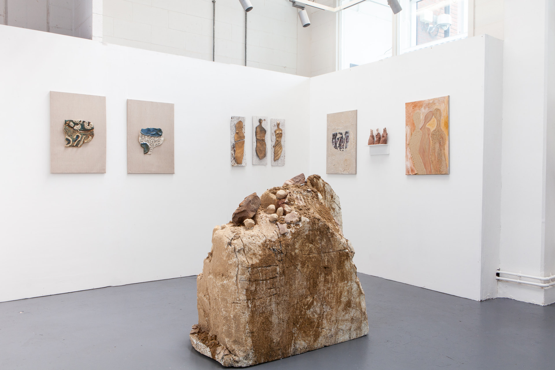 Wide gallery view of the Excavations exhibit with sculpture and wall pieces
