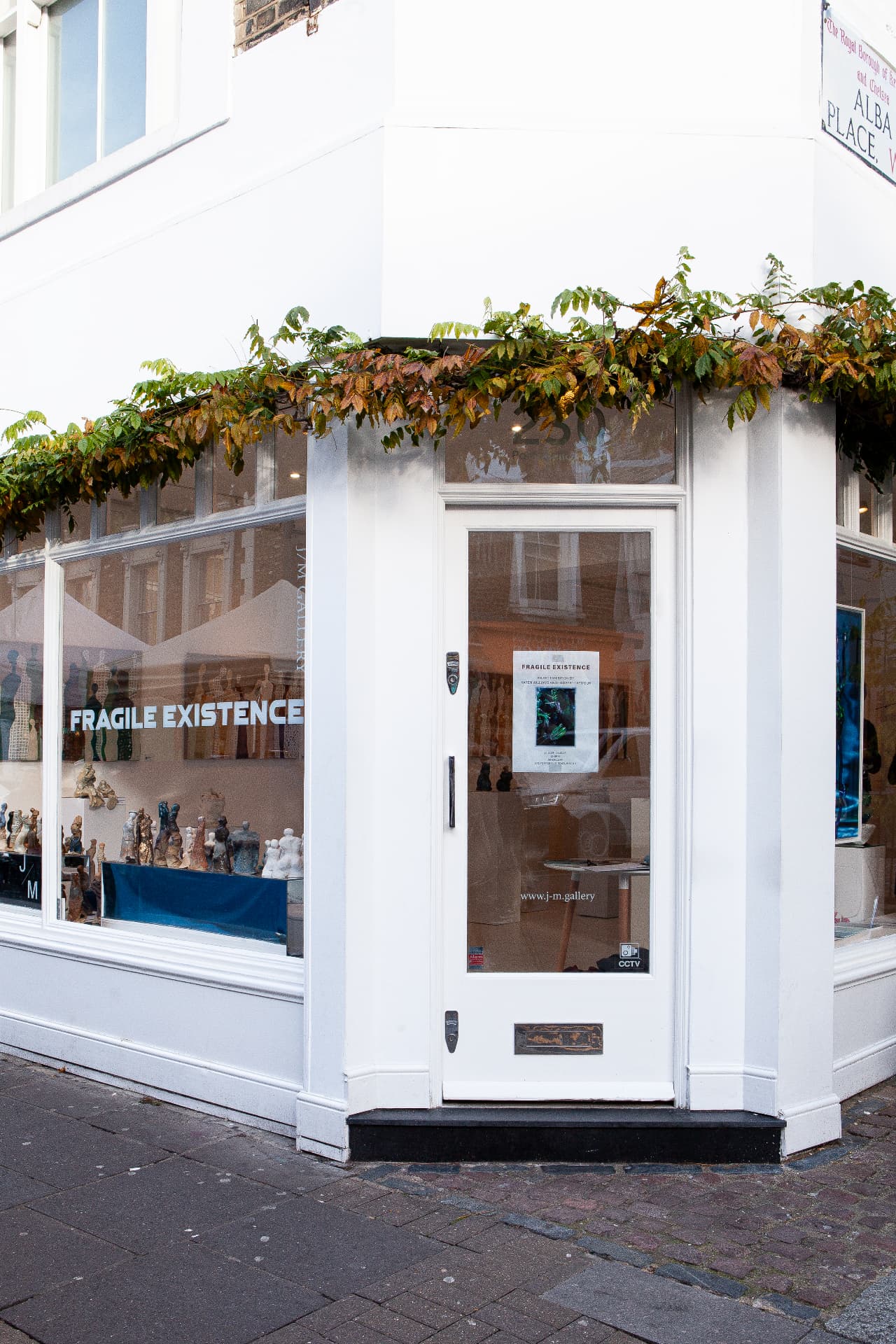 Gallery storefront with 'FRAGILE EXISTENCE' vinyl lettering on the window