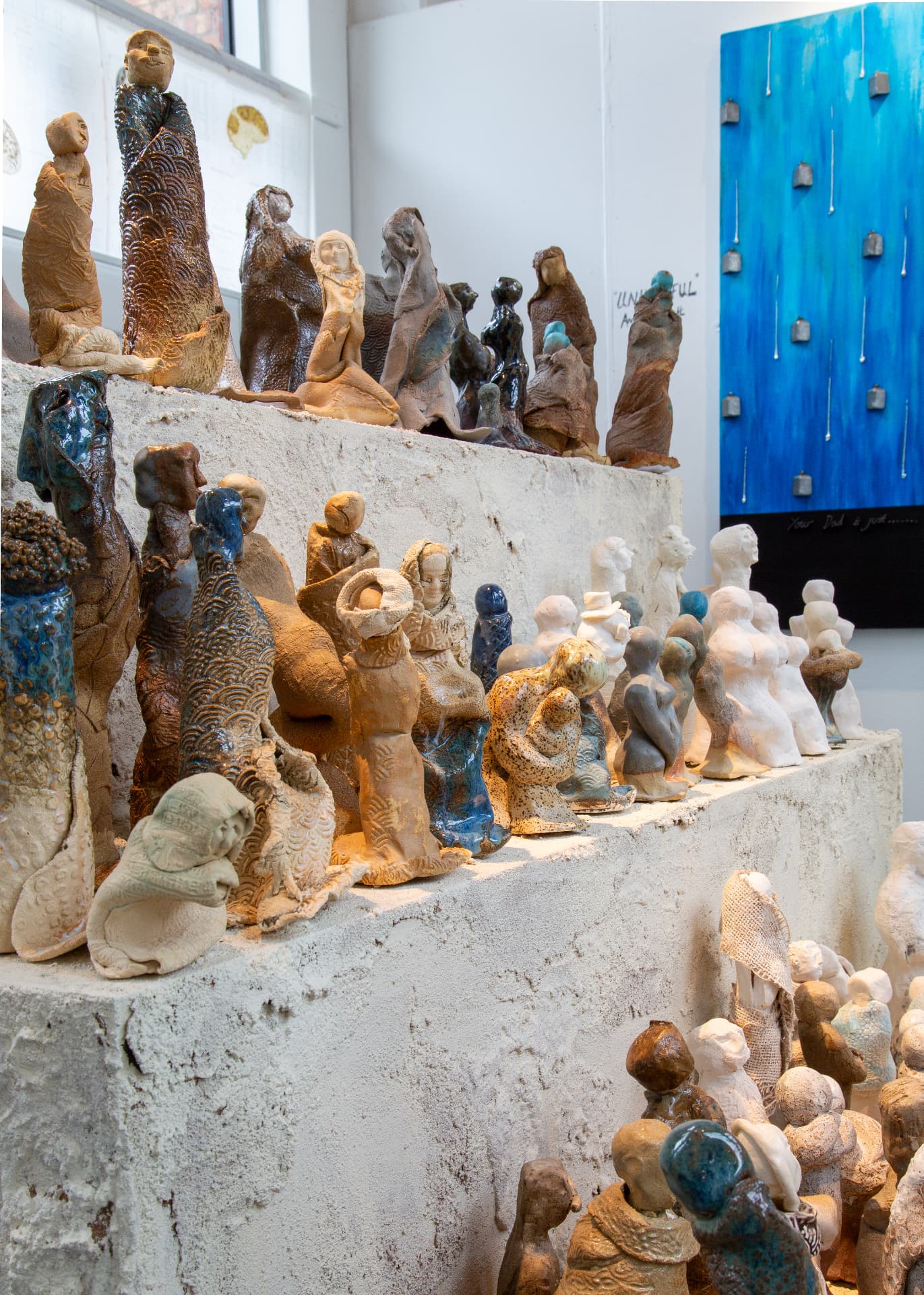 Rows of glazed ceramic figures arranged along plaster plinths
