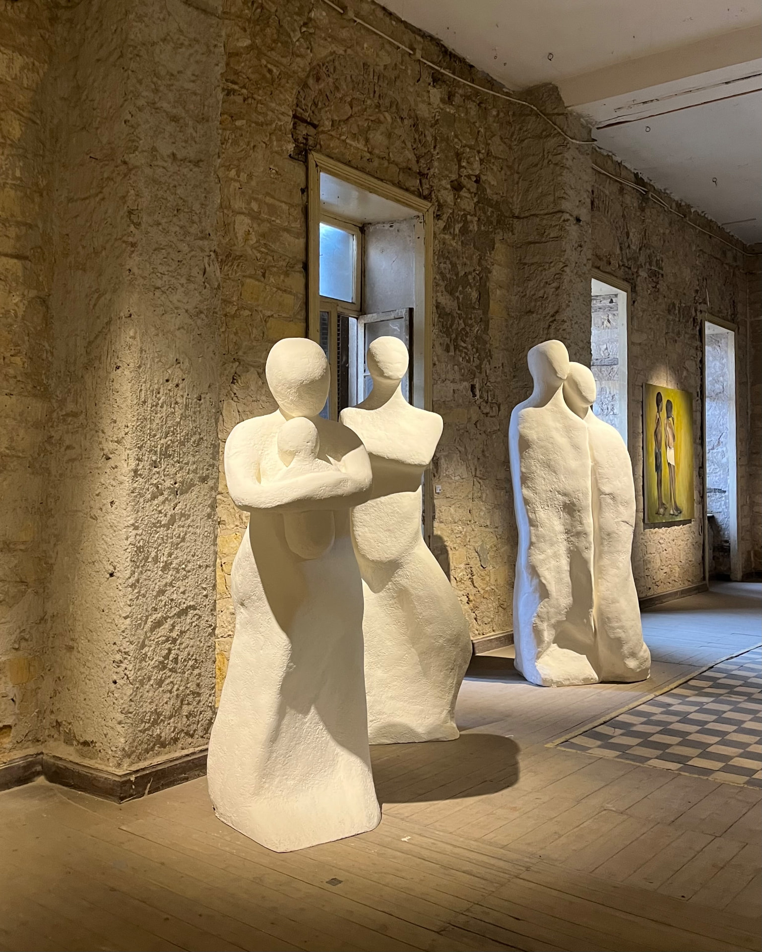 Three white plaster figures including a mother cradling a child