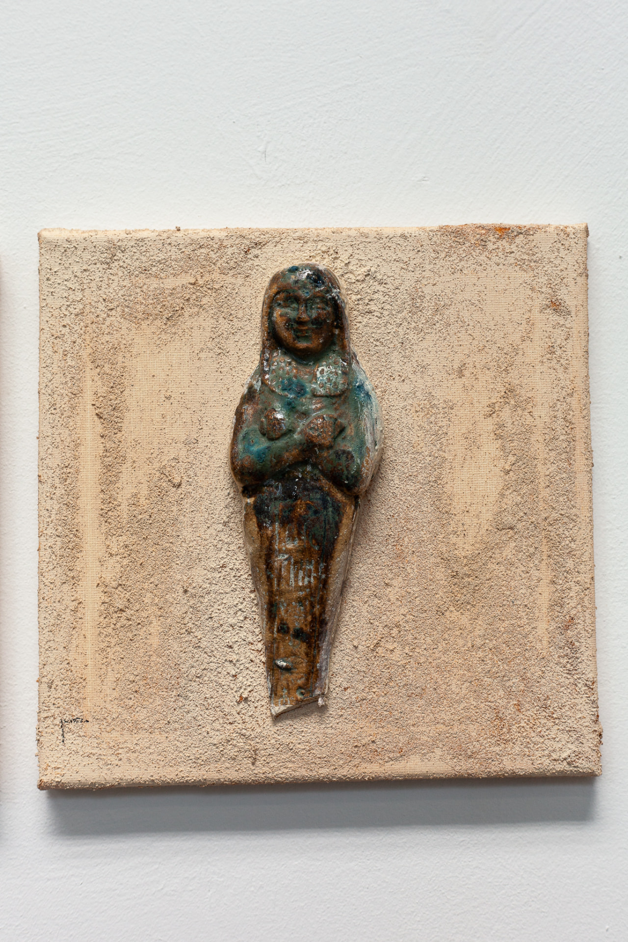 Single turquoise glazed ceramic figure mounted on a square canvas