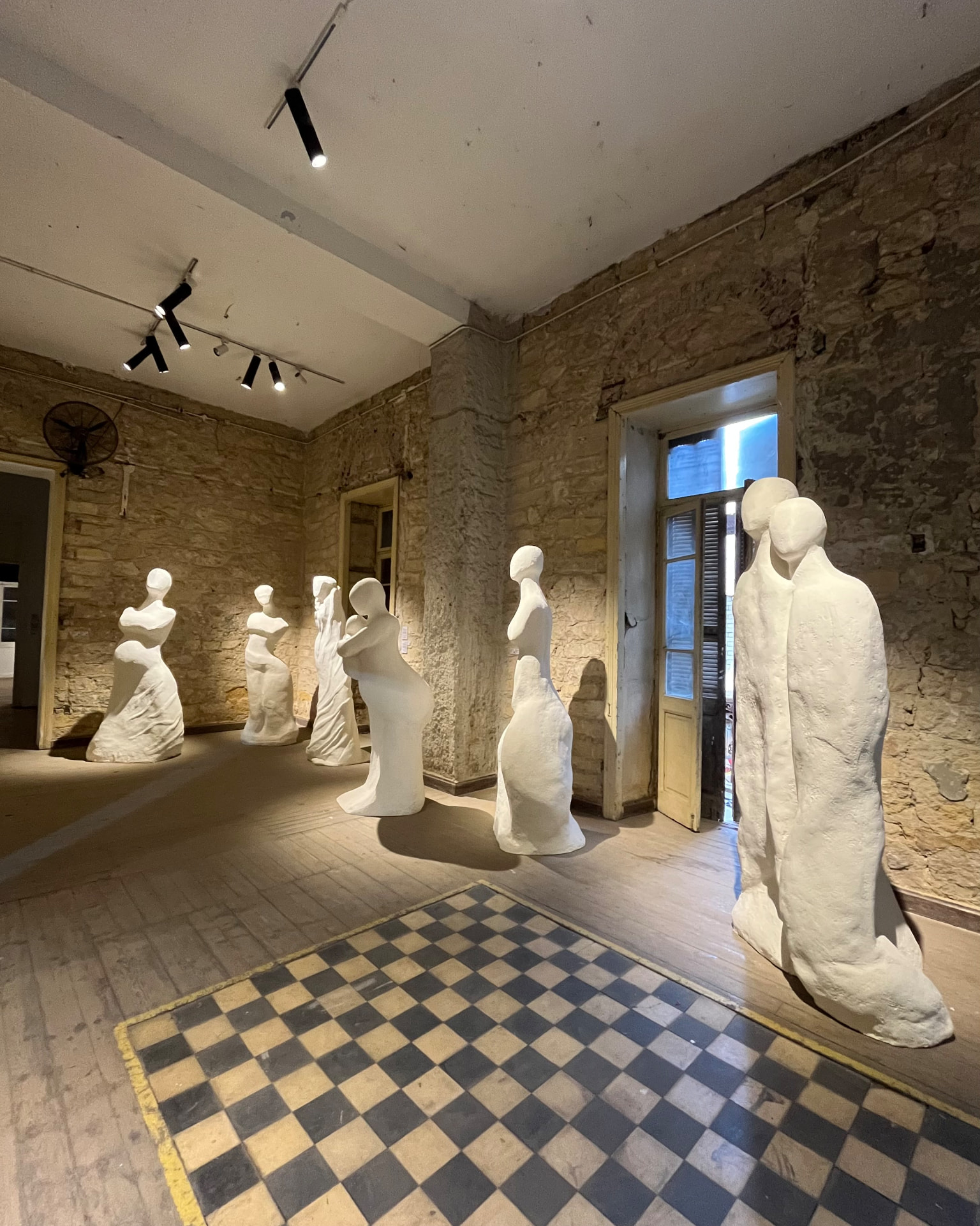 Gallery room filled with white plaster figure sculptures