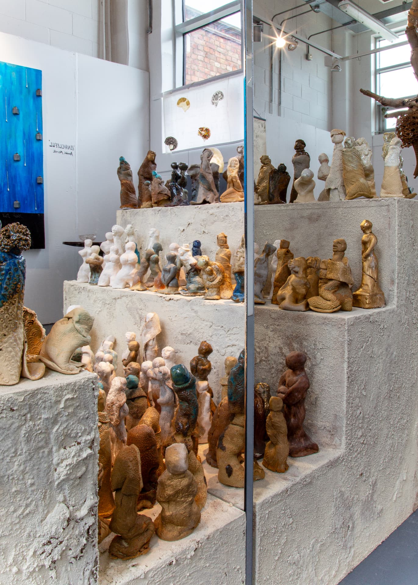 Installation of small ceramic figures on stepped plaster plinths