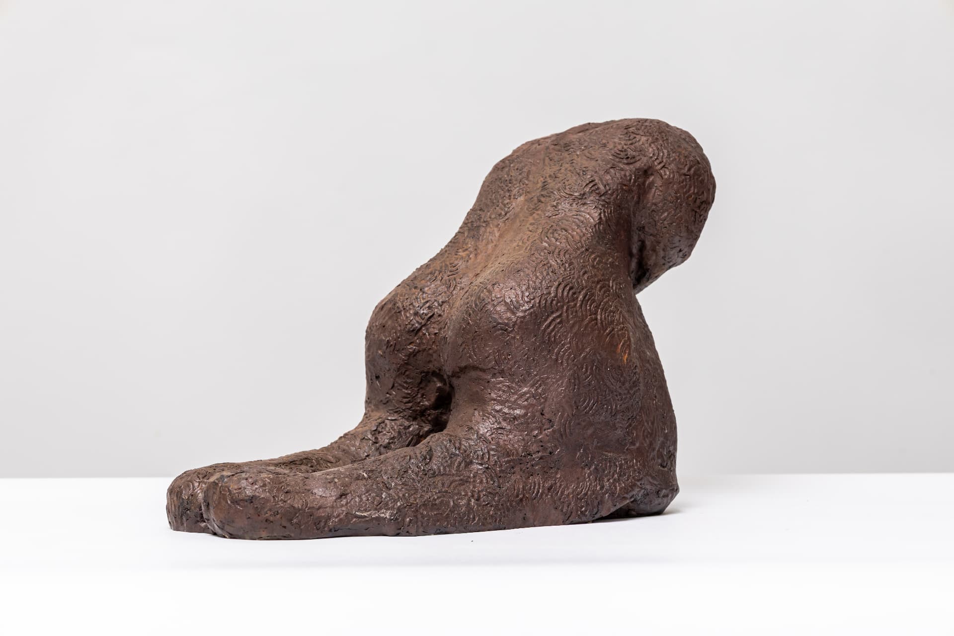 Grief, reclining bronze figure leaning forward