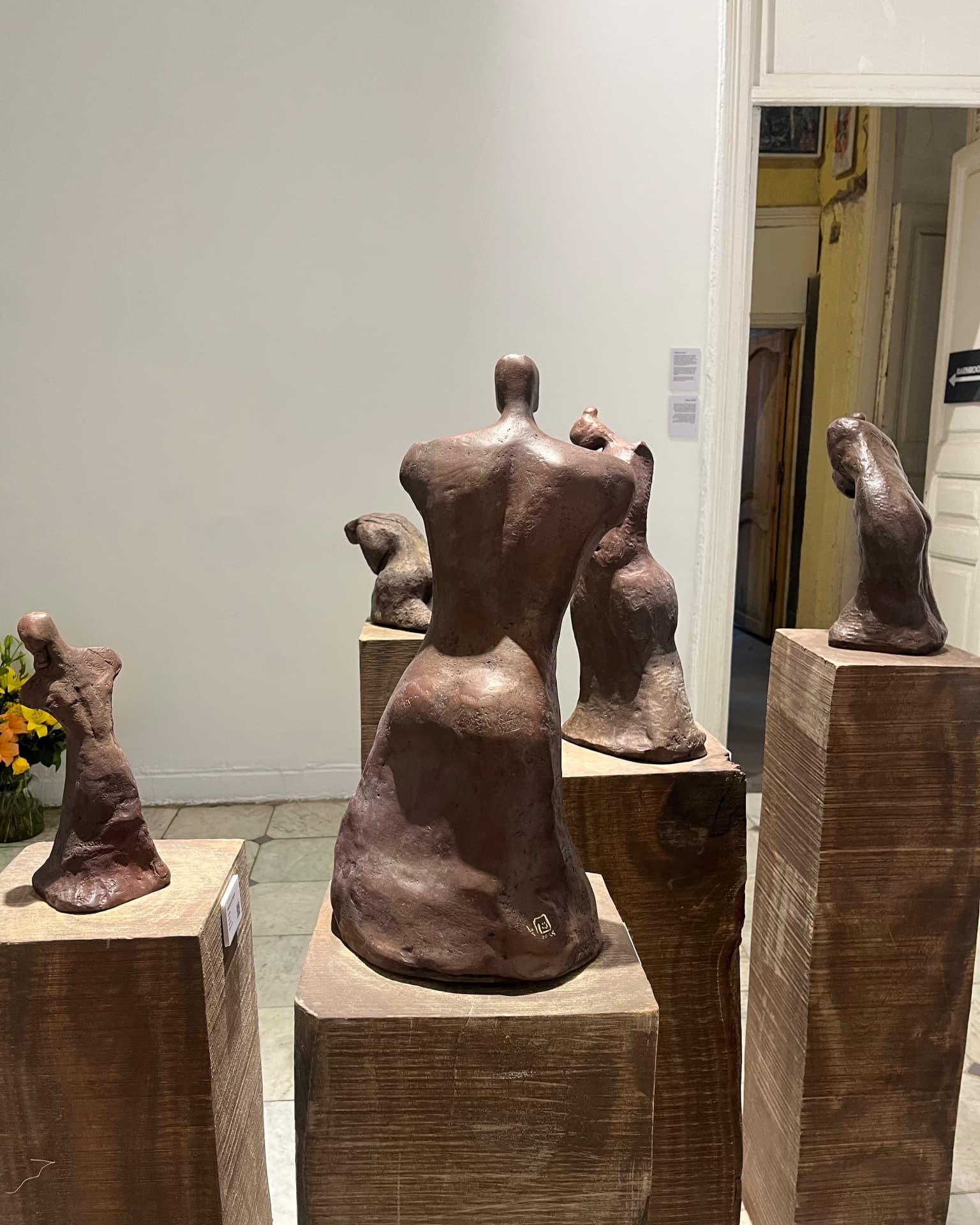 Back view of bronze torso sculptures on wooden plinths