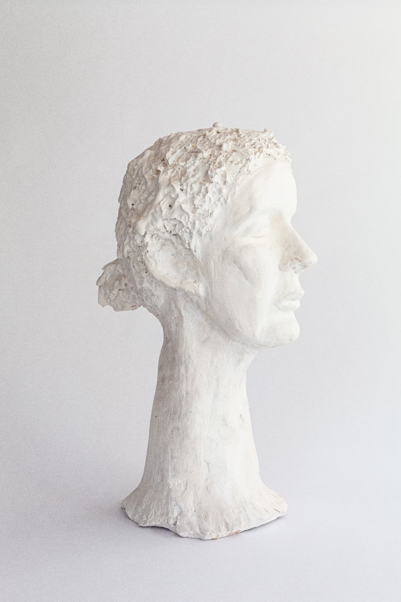 White plaster head of a woman with a long elegant neck, profile view